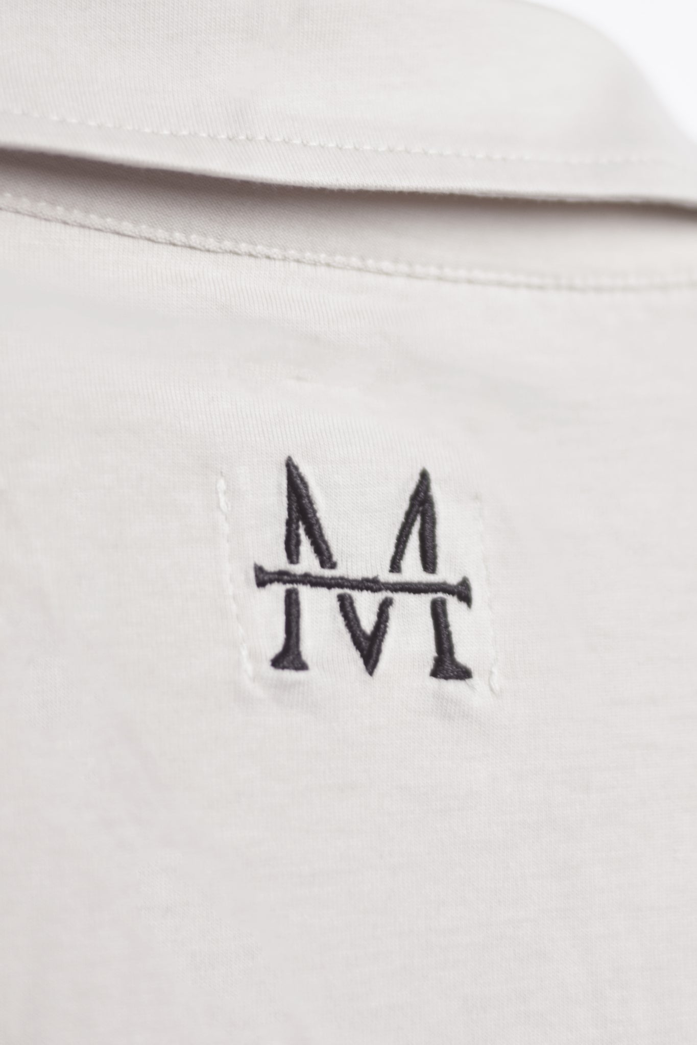 Load image into Gallery viewer, white shirt with a black embroidered
M logo